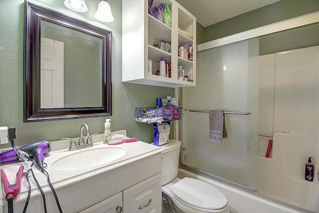 full bathroom with vanity, bath / shower combo with glass door, a textured ceiling, and toilet