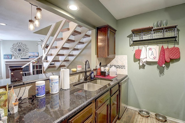 kitchen with dark stone counters, sink, tasteful backsplash, stainless steel dishwasher, and pendant lighting