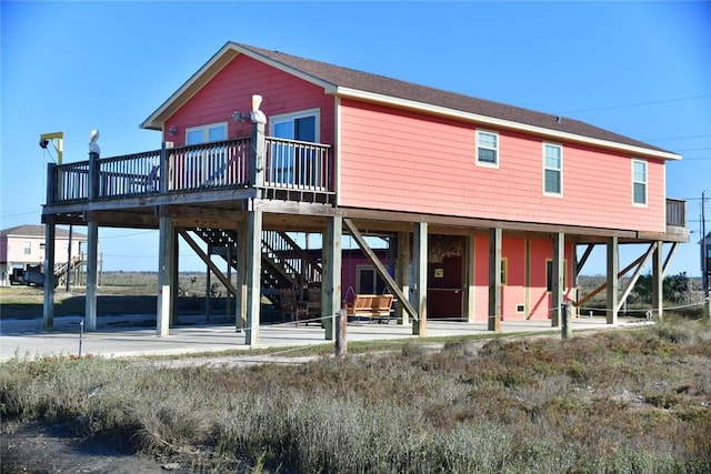 rear view of house featuring a deck, a carport, and stairway