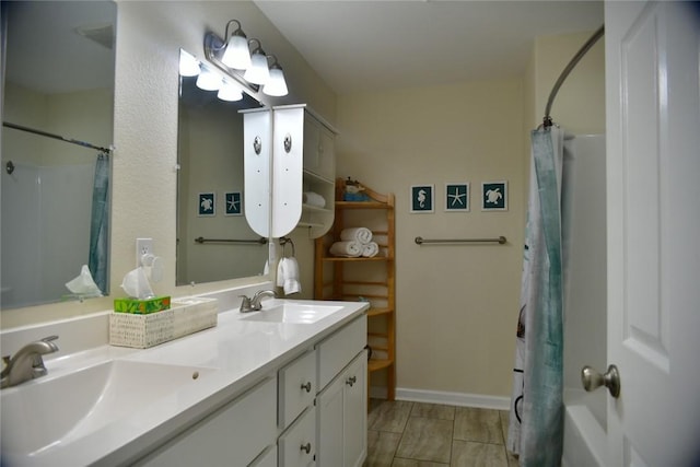 bathroom with a sink, baseboards, and double vanity