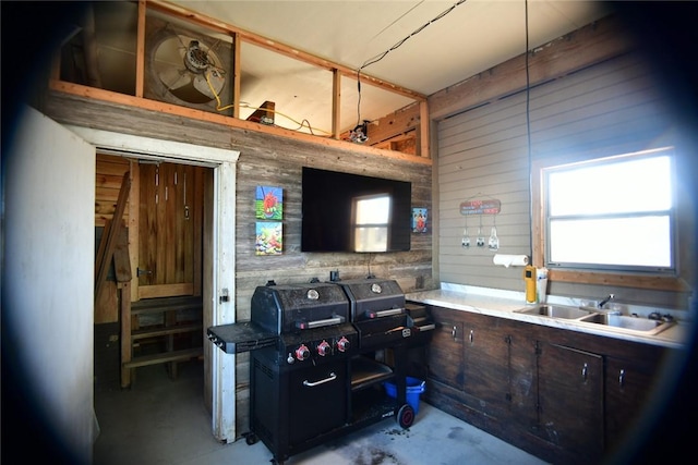 kitchen featuring concrete floors, a sink, and wood walls