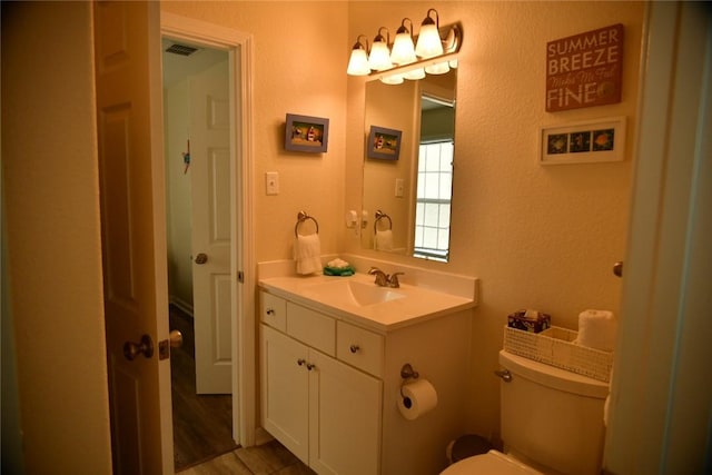 half bathroom featuring visible vents, vanity, and toilet