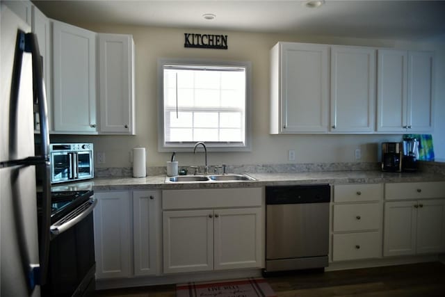 kitchen with stainless steel appliances, a sink, and white cabinetry