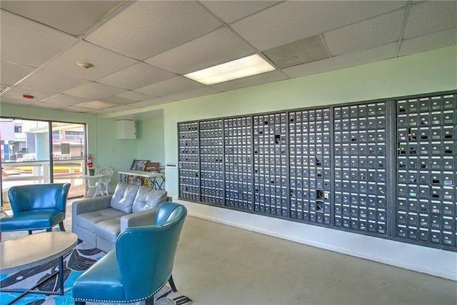 interior space with a drop ceiling, mail boxes, and concrete floors