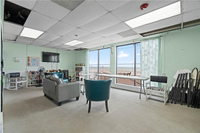 living room featuring a paneled ceiling and concrete floors