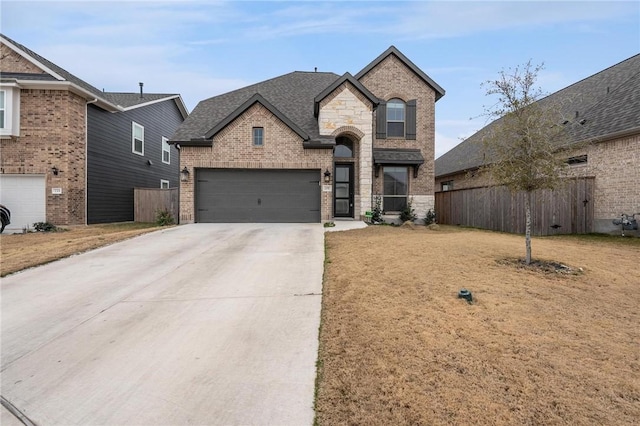 french country home featuring concrete driveway, fence, brick siding, and a shingled roof