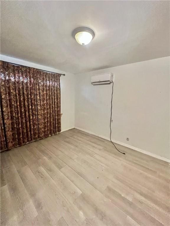 basement with an AC wall unit and light hardwood / wood-style flooring