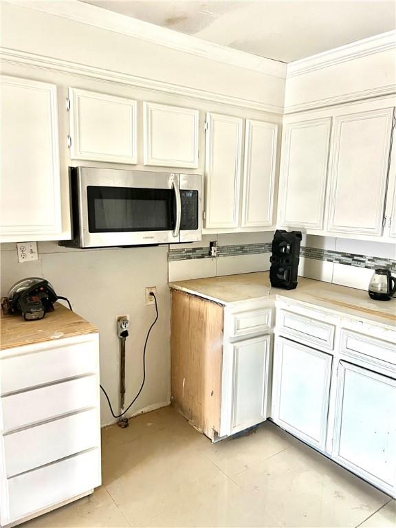 kitchen with white cabinetry, light tile patterned flooring, and ornamental molding