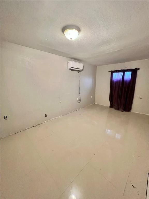 spare room featuring a textured ceiling and an AC wall unit