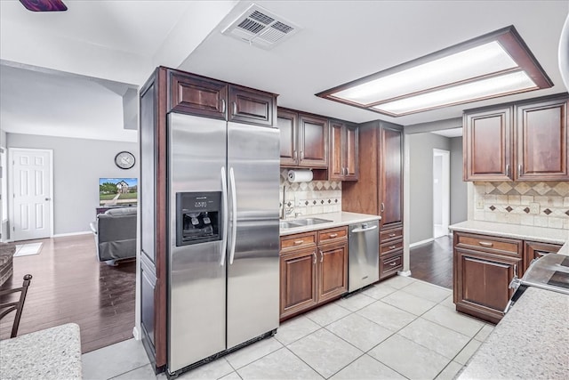 kitchen with stainless steel appliances, light hardwood / wood-style flooring, tasteful backsplash, and sink