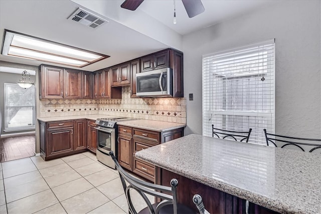 kitchen with decorative backsplash, a kitchen breakfast bar, stainless steel appliances, and light stone counters