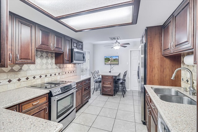 kitchen with backsplash, sink, ceiling fan, light tile patterned floors, and appliances with stainless steel finishes