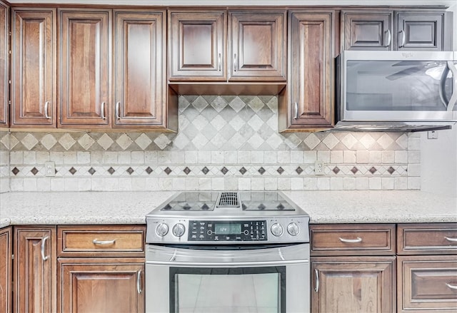 kitchen with light stone counters, appliances with stainless steel finishes, and tasteful backsplash