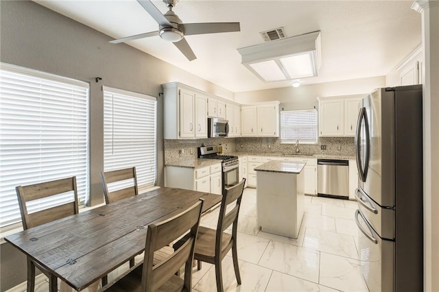 kitchen featuring stainless steel appliances, a center island, sink, and white cabinets