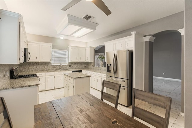 kitchen with white cabinetry, light stone countertops, a center island, and appliances with stainless steel finishes