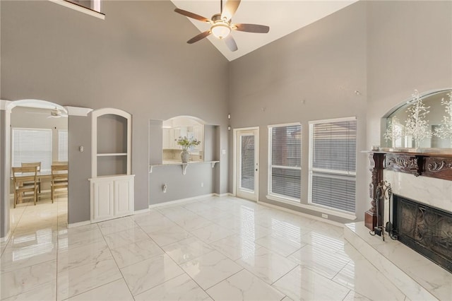 unfurnished living room with a premium fireplace, lofted ceiling, and ceiling fan