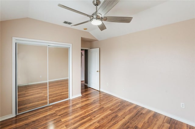 unfurnished bedroom with wood-type flooring, lofted ceiling, ceiling fan, and a closet