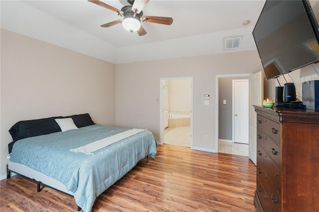 bedroom featuring ceiling fan, lofted ceiling, connected bathroom, and light hardwood / wood-style flooring