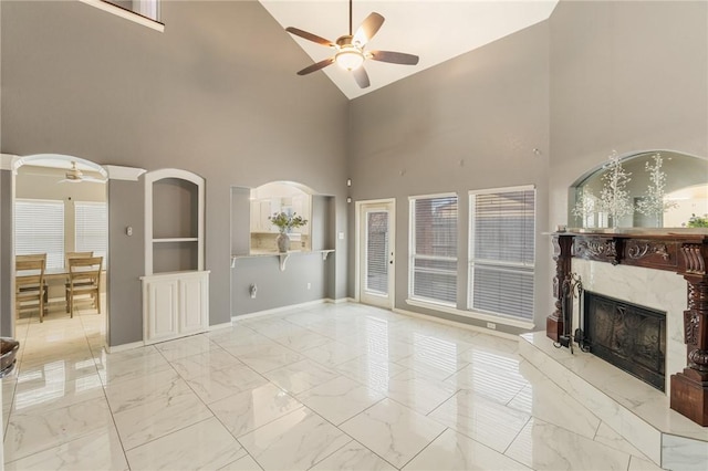 unfurnished living room with ceiling fan, a high end fireplace, and vaulted ceiling