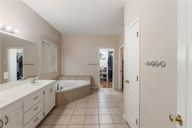 bathroom with tile patterned flooring, vanity, and tiled tub