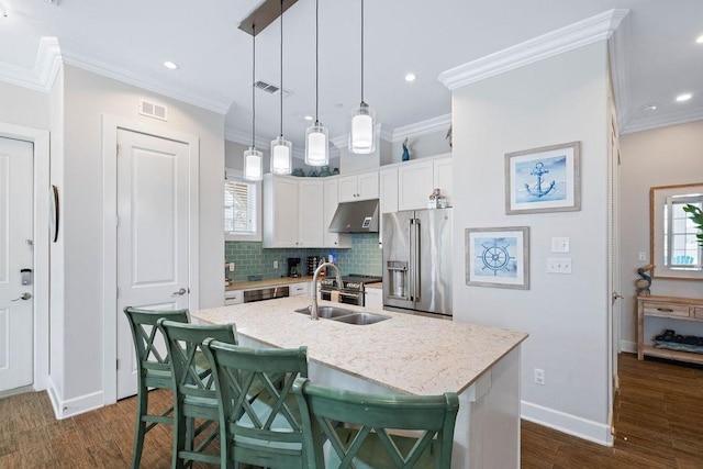 kitchen featuring high end refrigerator, ornamental molding, backsplash, and under cabinet range hood