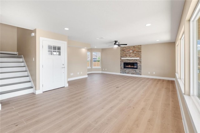 15334 Key Largo Ct, Corpus Christi, TX 78418 - unfurnished living room with ceiling fan, light wood-style flooring, baseboards, stairway, and a large fireplace
