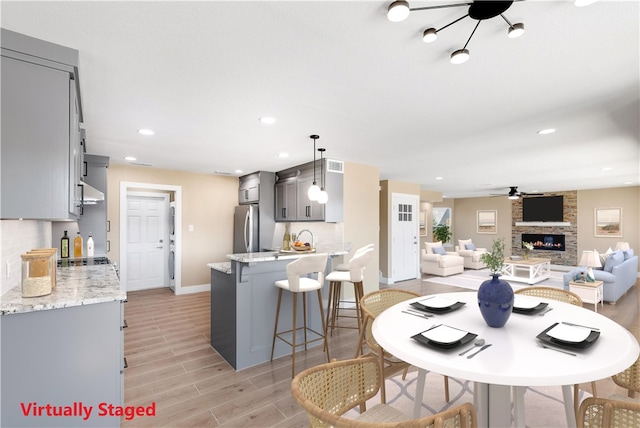 15334 Key Largo Ct, Corpus Christi, TX 78418 - dining area with ceiling fan, light wood finished floors, a stone fireplace, baseboards, and recessed lighting