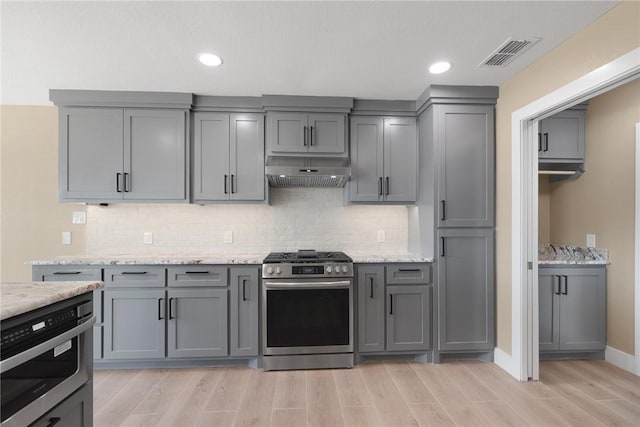 15334 Key Largo Ct, Corpus Christi, TX 78418 - kitchen with appliances with stainless steel finishes, under cabinet range hood, gray cabinets, light wood-style flooring, and tasteful backsplash
