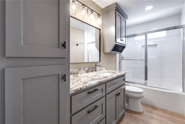 15334 Key Largo Ct, Corpus Christi, TX 78418 - bathroom with wood finished floors, toilet, vanity, bath / shower combo with glass door, and recessed lighting