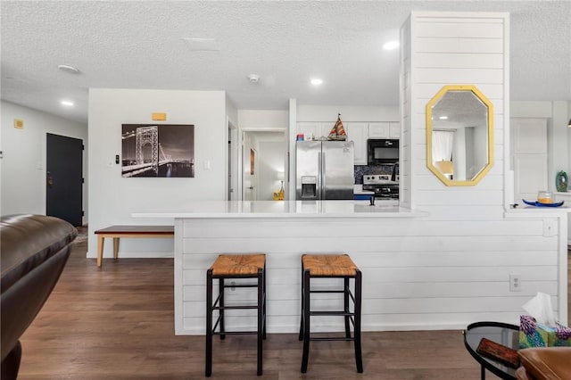 1400 Ocean Dr Unit 304C, Corpus Christi, TX 78404 - kitchen featuring appliances with stainless steel finishes, a breakfast bar, dark wood-style flooring, a peninsula, and a textured ceiling
