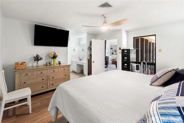 1400 Ocean Dr Unit 304C, Corpus Christi, TX 78404 - bedroom with light wood-type flooring, a textured ceiling, ensuite bathroom, and ceiling fan