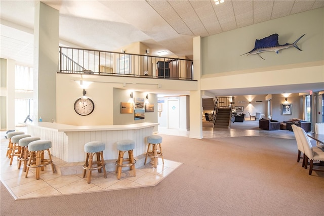 bar with light carpet and high vaulted ceiling