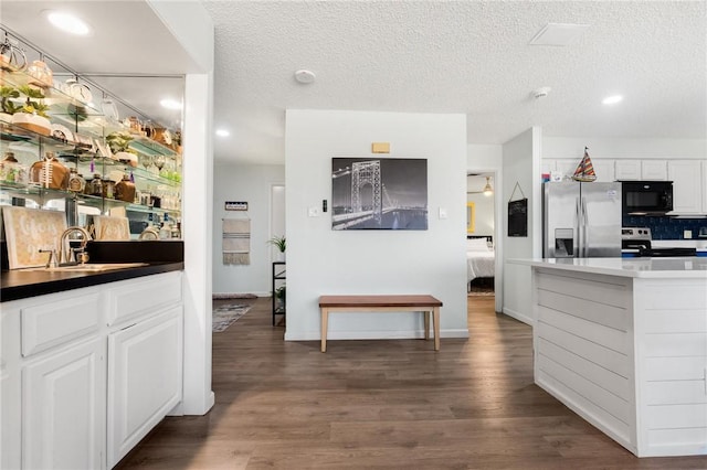 1400 Ocean Dr Unit 304C, Corpus Christi, TX 78404 - kitchen with stainless steel fridge with ice dispenser, black microwave, range with electric stovetop, white cabinets, and wood finished floors