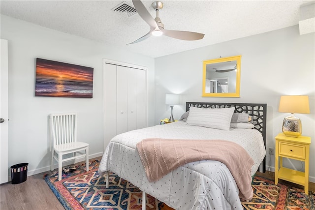 bedroom with ceiling fan, a closet, hardwood / wood-style floors, and a textured ceiling