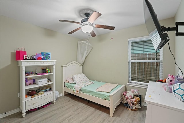 bedroom with light wood finished floors, baseboards, and a ceiling fan