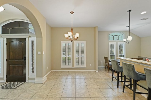 dining space featuring visible vents, baseboards, lofted ceiling, a chandelier, and light tile patterned flooring