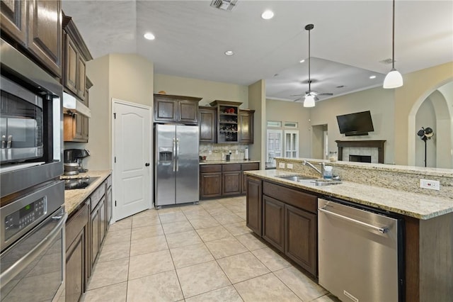 kitchen featuring stainless steel appliances, recessed lighting, backsplash, a sink, and dark brown cabinetry