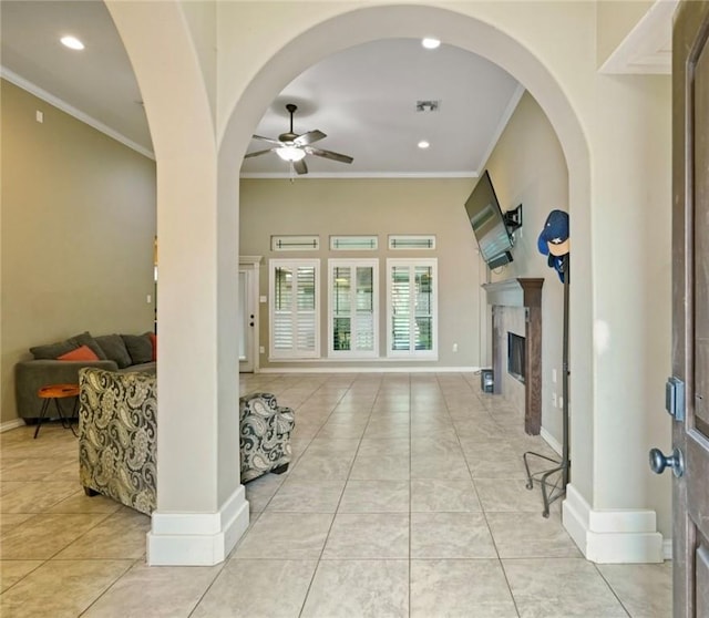 living room featuring ornamental molding, a premium fireplace, a ceiling fan, and baseboards