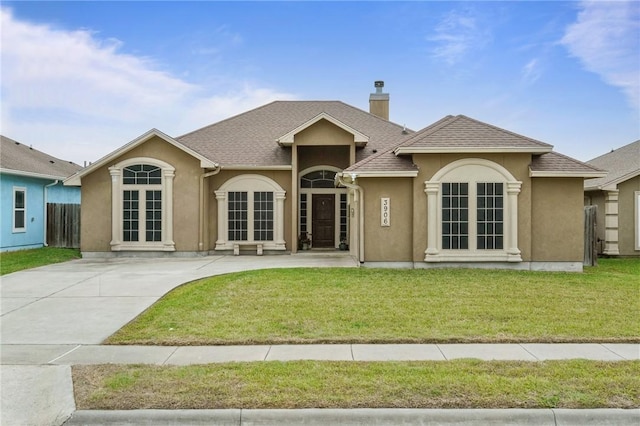 rear view of house with french doors, a chimney, stucco siding, a shingled roof, and a lawn