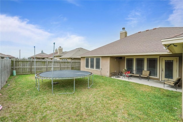 view of yard featuring a trampoline, a fenced backyard, and a patio