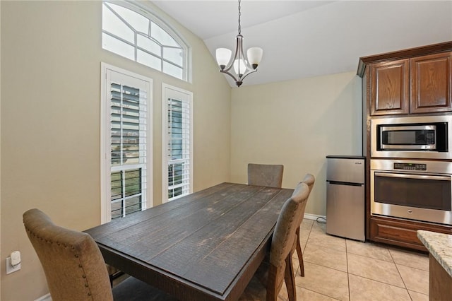 dining room with a wealth of natural light, light tile patterned flooring, vaulted ceiling, and an inviting chandelier