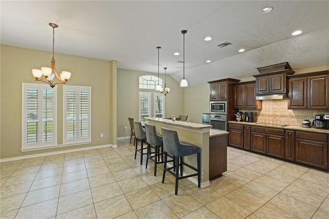 kitchen featuring a chandelier, under cabinet range hood, stainless steel appliances, visible vents, and tasteful backsplash