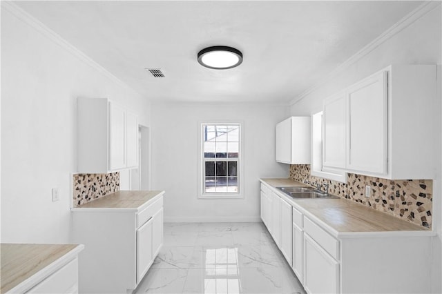 1113 Annapolis Dr, Corpus Christi, TX 78404 - kitchen featuring a sink, ornamental molding, light marble finish floors, light countertops, and white cabinets