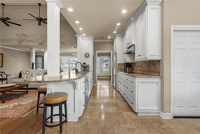 kitchen featuring appliances with stainless steel finishes, open floor plan, a peninsula, and ornate columns