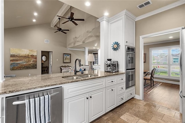 kitchen featuring lofted ceiling with beams, stainless steel appliances, a sink, visible vents, and light stone countertops