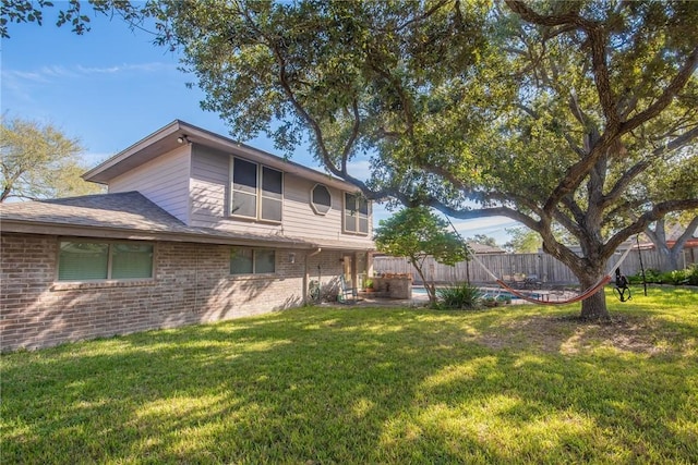 exterior space with a yard, fence, and brick siding