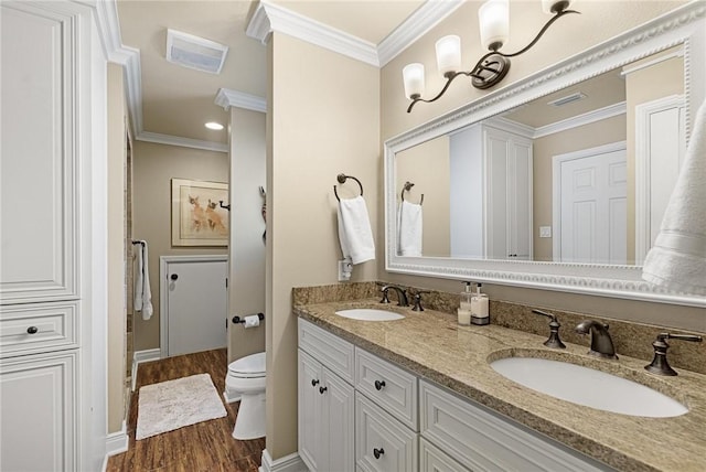 full bathroom with toilet, crown molding, visible vents, and a sink