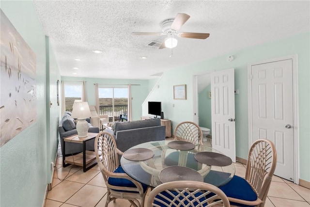 dining space with a textured ceiling, ceiling fan, light tile patterned flooring, visible vents, and baseboards