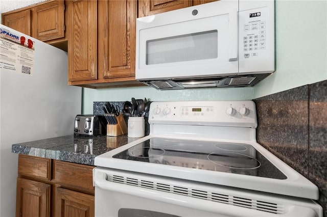 kitchen with dark countertops, white appliances, and brown cabinets