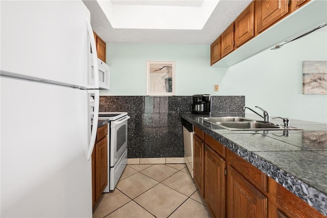 kitchen featuring white appliances, light tile patterned floors, tile counters, brown cabinets, and a sink